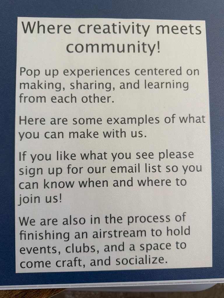 A hand-lettered sign reading about creativity at a market booth