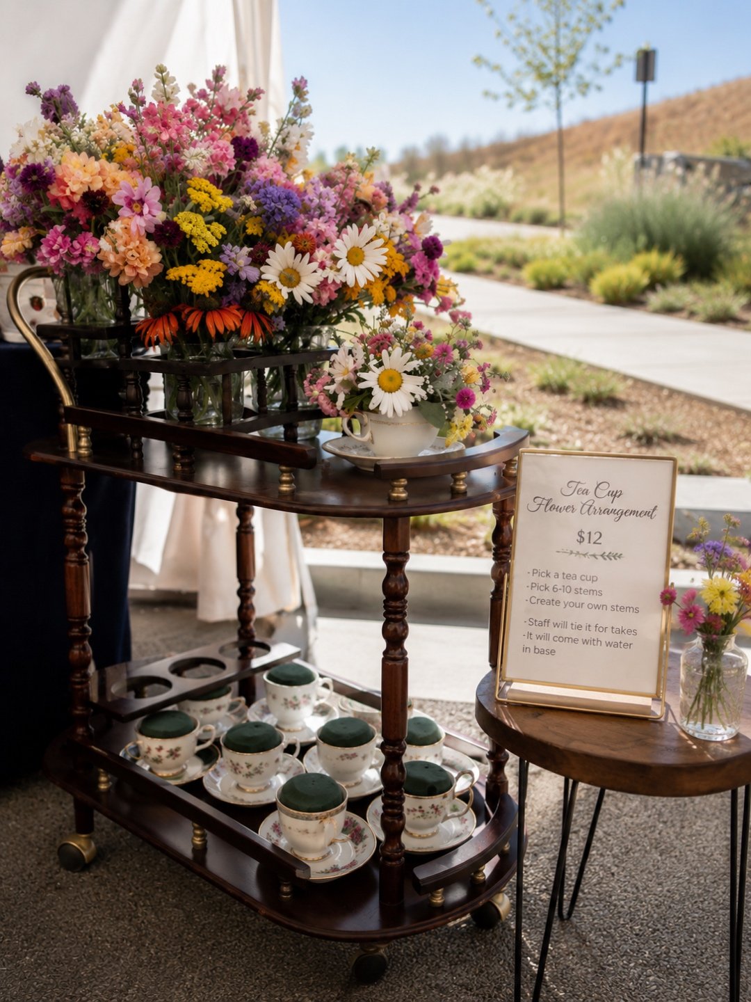 A cart displaying vintage teacups filled with fresh floral arrangements