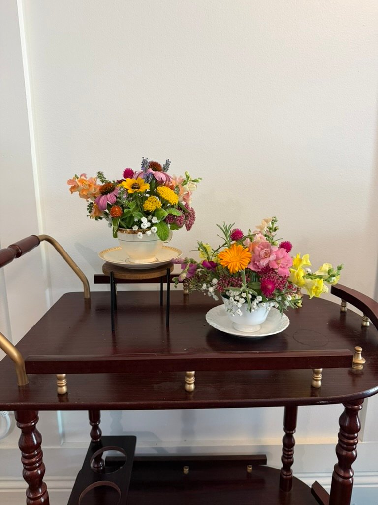 A styled cart of vintage teacups with fresh floral arrangements